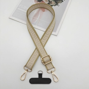 Detail view of woven adjustable phone strap with geometric jacquard and gold metal hardware