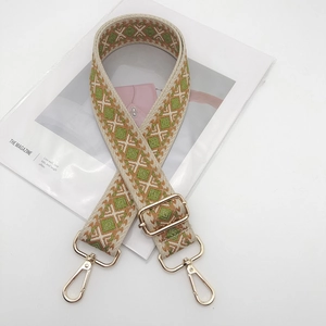 Macro detail of geometric patterned woven bag strap with light gold metal lobster clasps