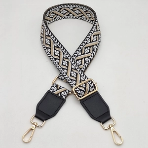 Detail of the golden metal snap hooks and geometric jacquard strap for crossbody bags