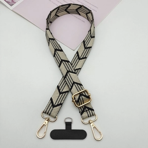 Close-up of black and white geometric arrow strap with gold metal hooks and phone patch