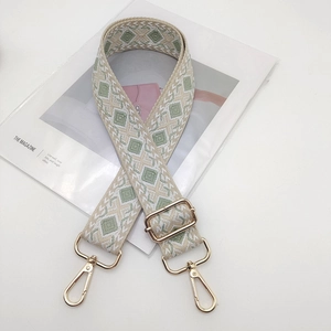 Detail view of wide woven shoulder strap with diamond pattern and gold metal hooks