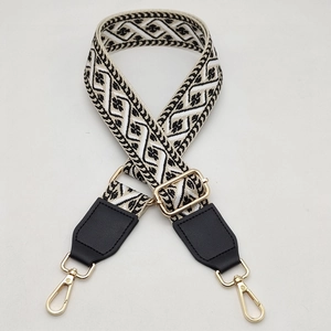 Detail of wide adjustable woven bag strap with golden hardware and ethnic pattern