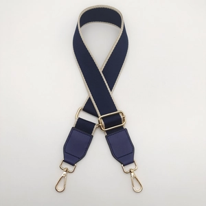 Detail of adjustable woven canvas bag strap in navy blue with gold metal hardware