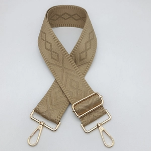 Detail of adjustable khaki woven shoulder strap with gold hardware and geometric pattern