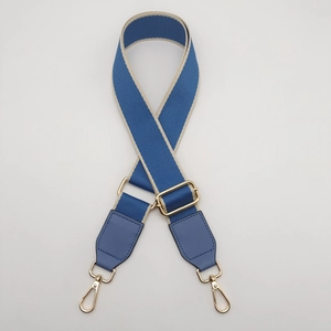 Close-up of blue and beige woven shoulder strap with gold metal buckle and leather ends