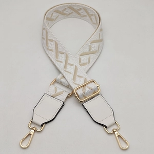 Detail of adjustable wide woven shoulder strap with gold metal hooks and white leather ends