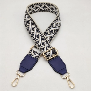 Detail of adjustable wide shoulder strap with beige floral jacquard and gold hardware