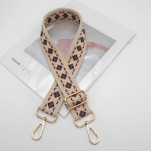 Detail of colorful geometric diamond pattern wide canvas bag strap with gold metal hooks