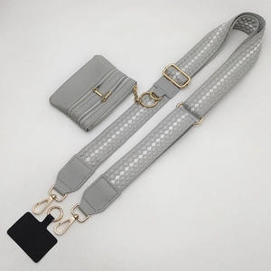 Detail view of adjustable polka dot shoulder strap with a small grey leather pouch and gold hardware