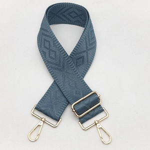 Detail of grey-blue woven strap with jacquard diamond pattern and gold metal buckles