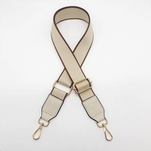 Close-up of adjustable canvas bag strap with golden metal clasps and leather ends