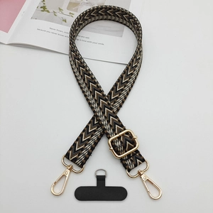 Détail d'une bandoulière tissée bohème avec crochets en métal doré et patch téléphone