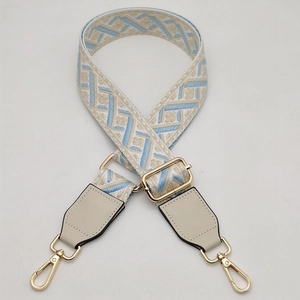 Detail of adjustable geometric jacquard bag strap with gold-tone rotating metal hooks