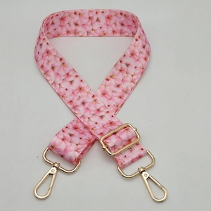 Detail of adjustable pink cherry blossom pattern bag strap with gold metal buckles
