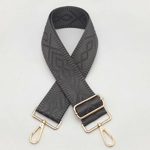 Detail of dark grey geometric woven canvas strap with adjustable golden metal buckles