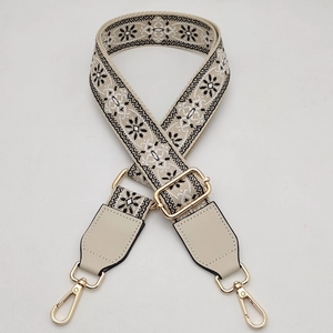 Close-up of woven ethnic bag strap with floral pattern and gold metal hardware