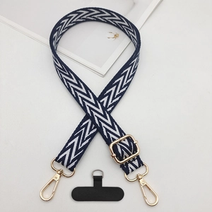 Detail of navy blue and white woven phone strap with gold hardware and T-shaped patch