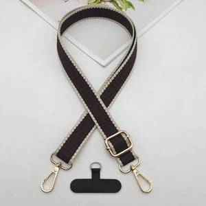 Detail of woven geometric pattern phone strap with adjustable gold metal buckle hardware