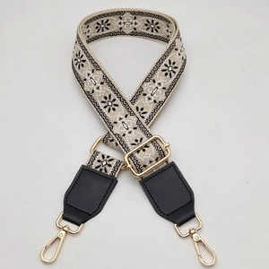 Detail of adjustable woven bag strap with ethnic floral pattern and gold metal hardware