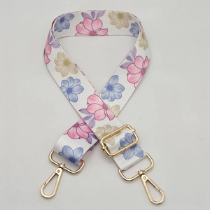 Close-up of adjustable floral strap with golden lobster clasps and colorful flower patterns