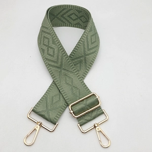 Close-up of olive green geometric jacquard bag strap with gold metal spring hooks