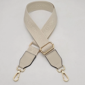 Detail of adjustable cream wide strap with floral jacquard pattern and gold metal buckles