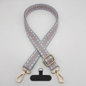 Detail of adjustable wide woven phone strap with geometric jacquard pattern and gold hooks