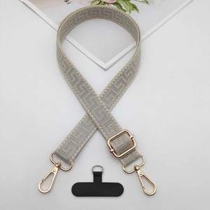 Close-up of adjustable grey geometric embroidered phone strap with gold metal hardware