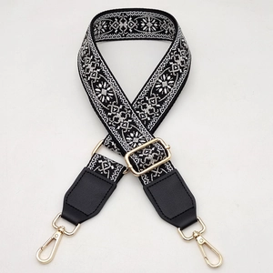 Close-up of ethnic embroidered bag strap with gold metal hooks and adjustable buckle