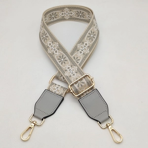 Close-up of adjustable ethnic floral embroidery bag strap with gold metal hooks