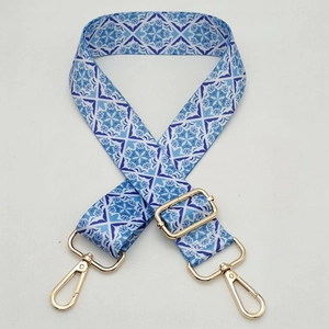 Detail of adjustable blue geometric floral shoulder strap with polished gold hardware hooks