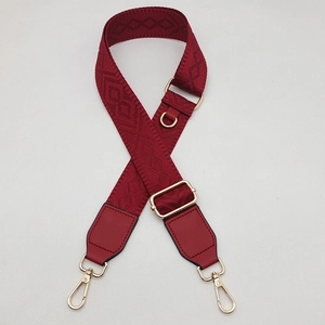 Détail de la bandoulière tissée rouge foncé réglable avec fermoir métallique doré brillant