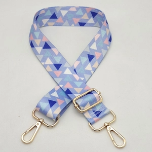 Detail of adjustable bag strap with blue geometric triangle pattern and gold lobster clasp
