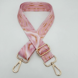 Detail of adjustable pink marble patterned handbag strap with gold metal buckles