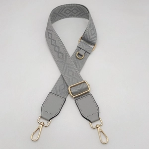 Détail de la bandoulière en jacquard gris avec motifs géométriques et boucles dorées