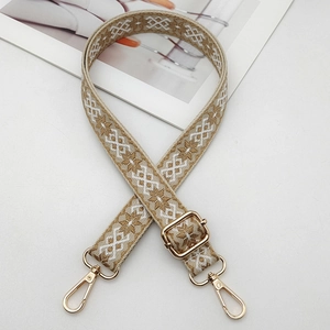Close-up of ethnic geometric woven strap with golden metal lobster clasps and buckles