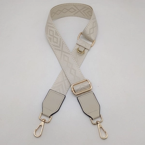 Détail de la bandoulière réglable avec motif de losanges beige et crochets dorés