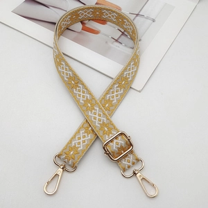 Close-up of yellow and beige ethnic embroidery strap with golden metal swivel hooks