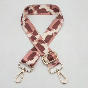 Close-up of wide nylon guitar strap with giraffe print and gold metal buckles