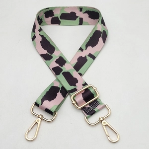 Close-up of wide colorful patterned strap with pink and green accents and gold hardware