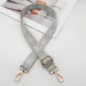 Detail of blue geometric embroidered bag strap with light gold metal swivel hooks