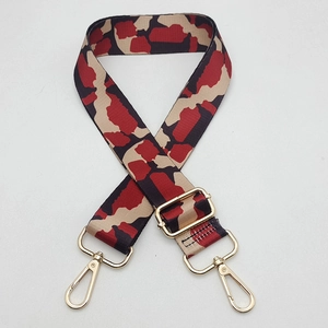 Close-up of wide adjustable bag strap with red camouflage print and golden metal hooks
