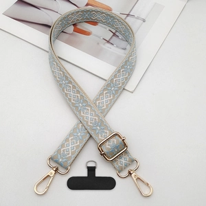 Close-up of jacquard phone strap with geometric pattern and golden metal swivel hooks