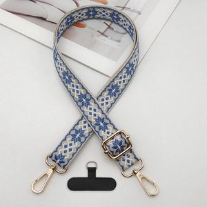 Detail of bohemian jacquard phone strap with gold hardware and geometric embroidery