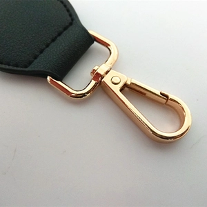 Detailed macro view of black lychee leather strap with polished gold lobster clasp swivel