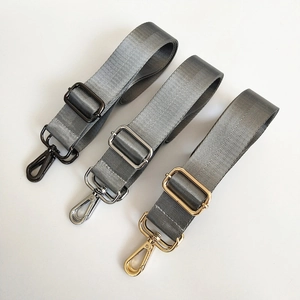 Nylon bag strap detail with herringbone weave and gunmetal, silver, and gold clips