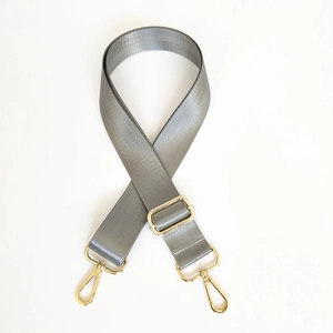 Macro detail of wide grey nylon bag strap with herringbone weave and gold swivel hooks