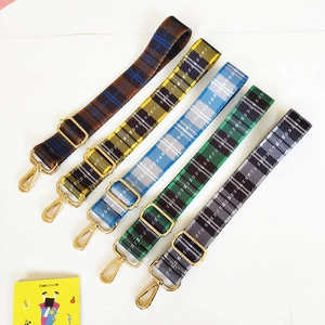 Detail view of five adjustable plaid nylon bag straps in various colors with gold hardware