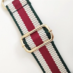 Close-up of adjustable striped woven shoulder strap with gold metal hooks and texture