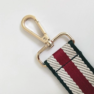 Close-up of replacement strap featuring green and red stripes with gold metal lobster clasp